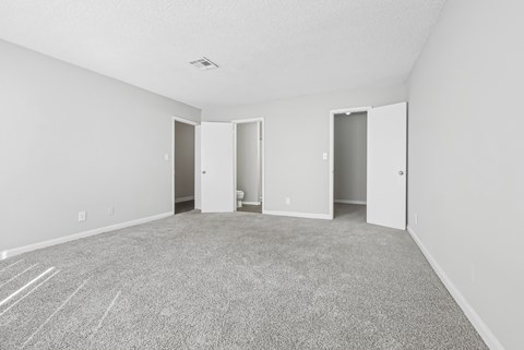 Our spacious master bedroom with carpeted floor and en suite bathroom in C2b floor plan at Riverwood Crossing apartments in Roswell, GA.